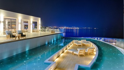 Night view of the luxurious Abaton Island Resort & Spa, showcasing a stunning illuminated infinity pool with stylish seating areas overlooking the serene, sparkling sea. Night view of the luxurious Abaton Island Resort & Spa, showcasing a stunning illuminated infinity pool with stylish seating areas overlooking the serene, sparkling sea.