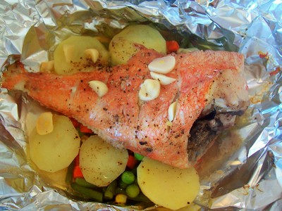 A delicious baked fish dish: red snapper seasoned with garlic and herbs, served with tender potatoes, peas, carrots, and green beans, all wrapped and cooked in foil. A delicious baked fish dish: red snapper seasoned with garlic and herbs, served with tender potatoes, peas, carrots, and green beans, all wrapped and cooked in foil.