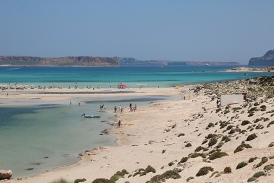 Panoramic view of Balos Lagoon in Crete, featuring turquoise waters, white sandy beaches, and visitors enjoying the serene natural beauty.