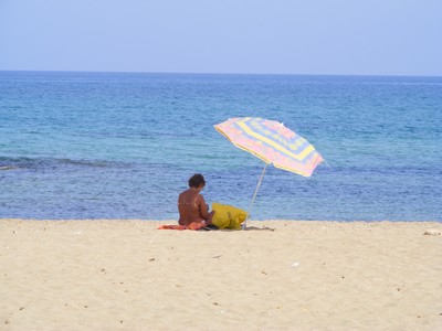 Person sat under an umbrella on the beach