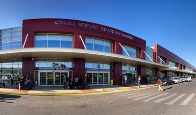 Exterior view of Chania International Airport, showcasing its modern facade with bold red accents, glass windows, and bustling entrances with travelers. Exterior view of Chania International Airport, showcasing its modern facade with bold red accents, glass windows, and bustling entrances with travelers.