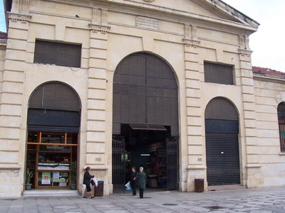 The entrance to Chania Indoor Market in Crete, featuring a grand arched doorway and historic architectural details, with a few people standing outside. The entrance to Chania Indoor Market in Crete, featuring a grand arched doorway and historic architectural details, with a few people standing outside.