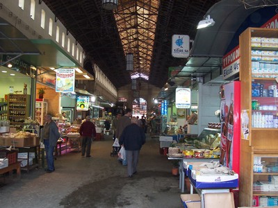 Interior view of Chania Market in Crete, showcasing various stalls with local produce, cheeses, and goods, as shoppers browse through the bustling indoor market. Interior view of Chania Market in Crete, showcasing various stalls with local produce, cheeses, and goods, as shoppers browse through the bustling indoor market.
