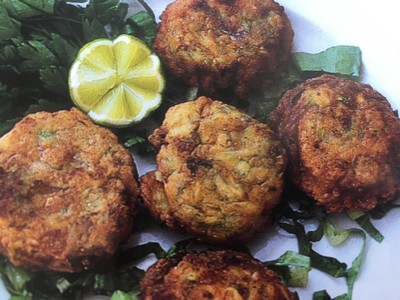 Crispy golden-brown Cretan courgette fritters served on a bed of fresh green herbs with a lemon wedge for garnish. Crispy golden-brown Cretan courgette fritters served on a bed of fresh green herbs with a lemon wedge for garnish.
