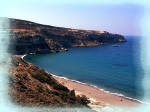 Panoramic view of the secluded nudist sandy beach at Komos, Crete, with crystal-clear blue waters, surrounded by rugged cliffs and natural vegetation. Panoramic view of the secluded nudist sandy beach at Komos, Crete, with crystal-clear blue waters, surrounded by rugged cliffs and natural vegetation.