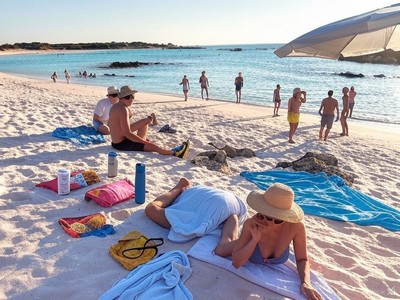 Visitors relaxing on the pink-tinged sands of Elafonissi Beach, Crete, with clear turquoise waters and a sunny sky in the background. Visitors relaxing on the pink-tinged sands of Elafonissi Beach, Crete, with clear turquoise waters and a sunny sky in the background.