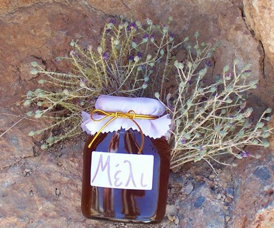A jar of Cretan thyme honey labeled 'Μέλι' (Greek for honey), placed against a backdrop of aromatic dried herbs, showcasing Crete's natural sweetness. A jar of Cretan thyme honey labeled 'Μέλι' (Greek for honey), placed against a backdrop of aromatic dried herbs, showcasing Crete's natural sweetness.