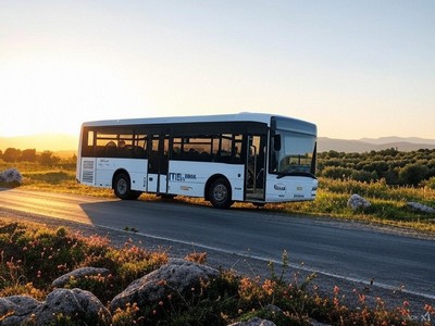A KTEL bus traveling through the scenic Cretan countryside at sunset, with wildflowers and rolling hills in the background. A KTEL bus traveling through the scenic Cretan countryside at sunset, with wildflowers and rolling hills in the background.