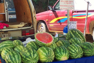 Fresh watermelons displayed at a local Cretan market, with a sliced melon showcasing its vibrant red interior. Fresh watermelons displayed at a local Cretan market, with a sliced melon showcasing its vibrant red interior.