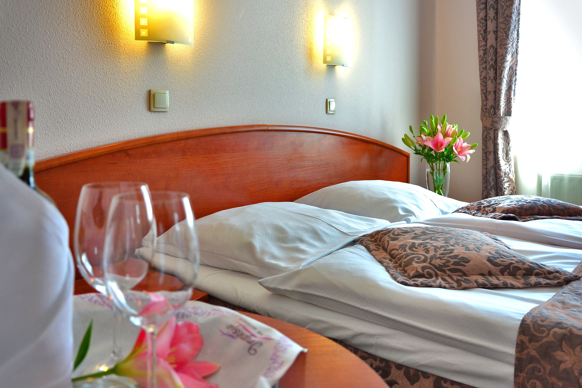 Cozy and elegantly decorated hotel room with fresh flowers on the bedside table, soft lighting, and glasses set for a relaxing stay. A good representation of luxury hotels In Crete. Cozy and elegantly decorated hotel room with fresh flowers on the bedside table, soft lighting, and glasses set for a relaxing stay. A good representation of luxury hotels In Crete.