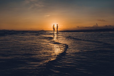 Silhouetted couple holding hands on a serene beach at sunset, with gentle waves and a golden sky creating a romantic atmosphere. Silhouetted couple holding hands on a serene beach at sunset, with gentle waves and a golden sky creating a romantic atmosphere.