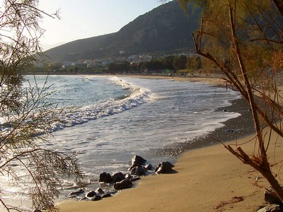 A secluded beach in Crete, with golden sand, gentle waves, and a backdrop of trees and hills, creating a serene and picturesque setting. A secluded beach in Crete, with golden sand, gentle waves, and a backdrop of trees and hills, creating a serene and picturesque setting.