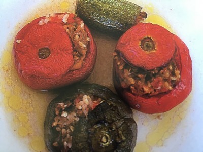 A close-up of traditional Cretan stuffed vegetables, featuring vibrant red tomatoes, green bell pepper, and zucchini filled with a savory mixture of rice and herbs, drizzled with olive oil. A close-up of traditional Cretan stuffed vegetables, featuring vibrant red tomatoes, green bell pepper, and zucchini filled with a savory mixture of rice and herbs, drizzled with olive oil.