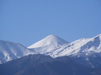Snow-capped peaks of the White Mountains of Crete against a clear blue sky.
