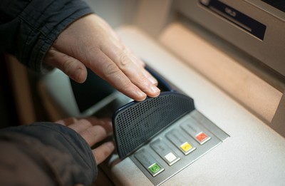 A person guarding the number pad when withdrawng cash from ATM